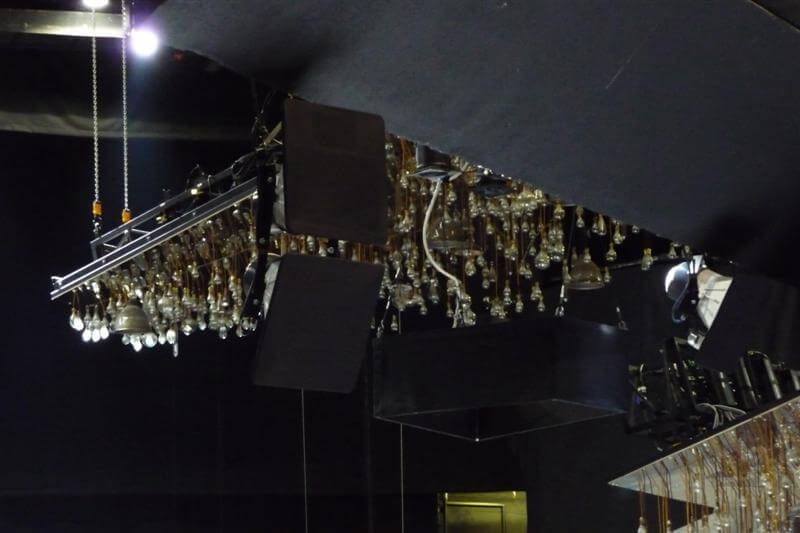 Close-up of complex overhead light rig with suspended fixtures and black sound panels.