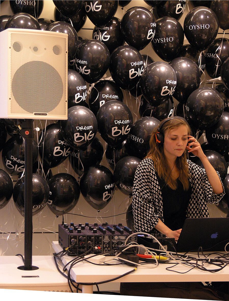 Female DJ mixing music in a club-style setup with branded decor