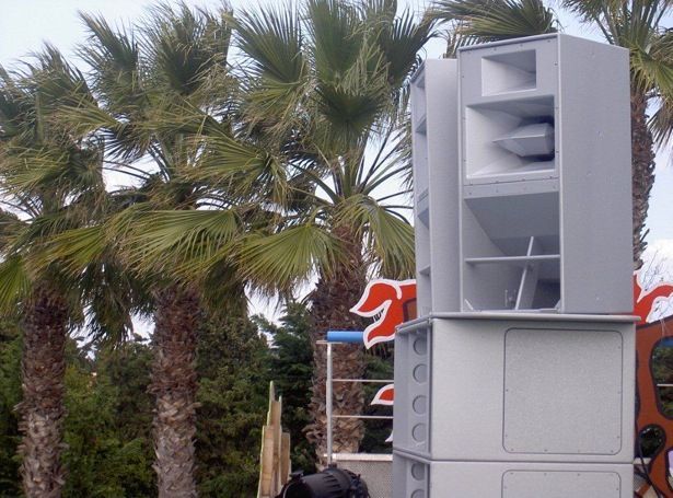 Large outdoor speaker system setup near palm trees and themed decor.