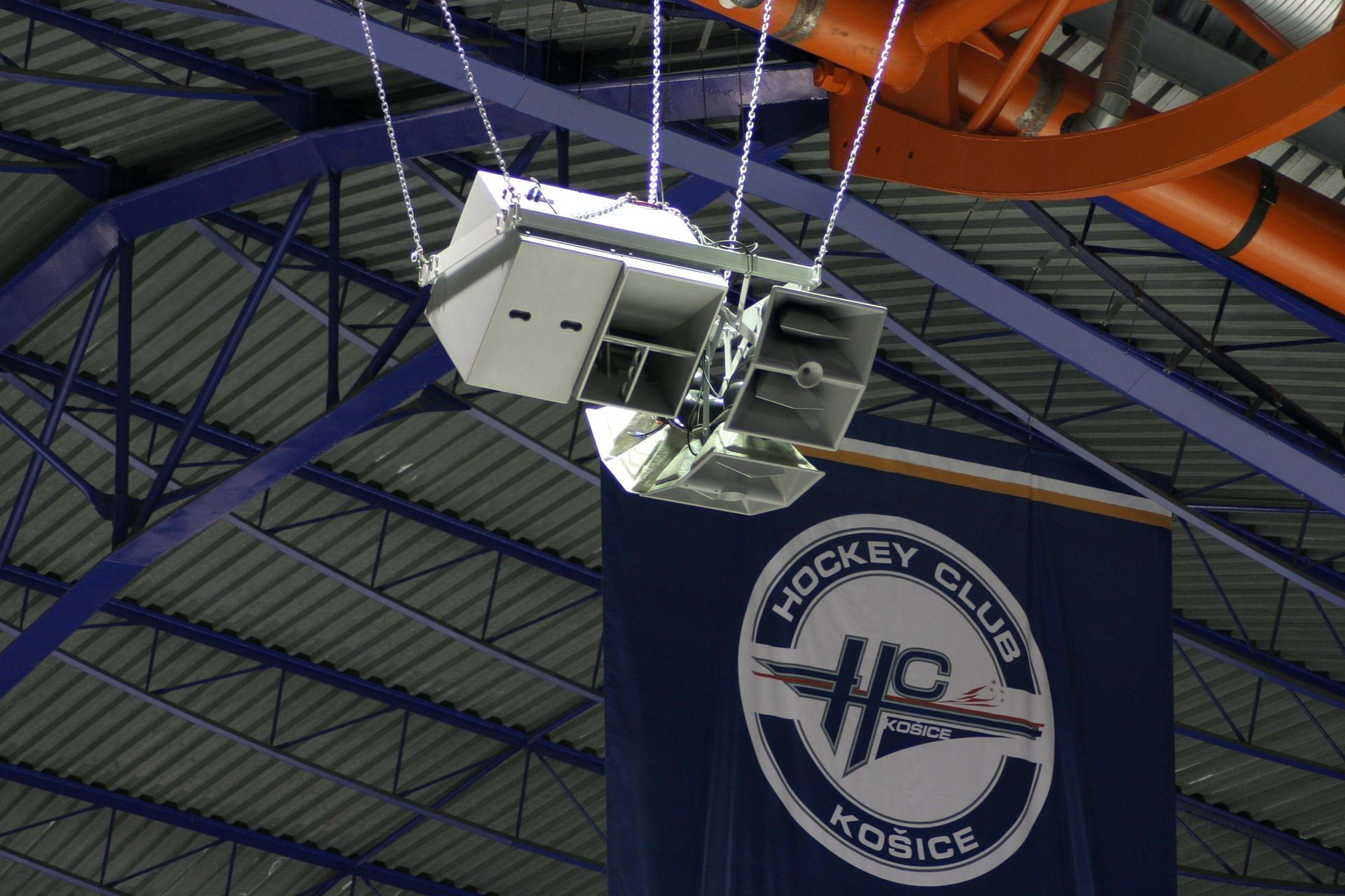 A tall metal light pole stands beside a modern building.