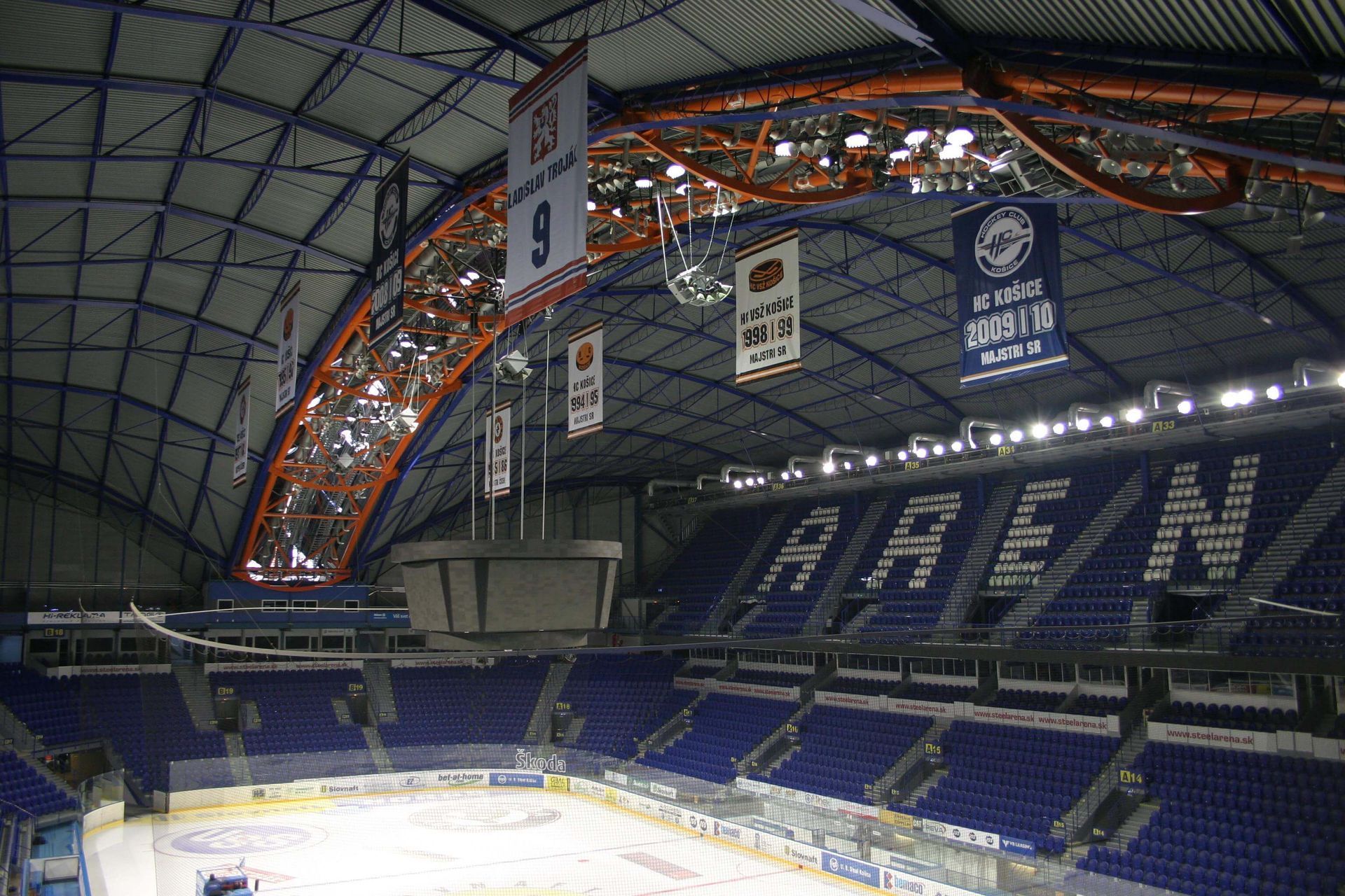 Interior of an empty ice hockey arena with dark blue seats and 
