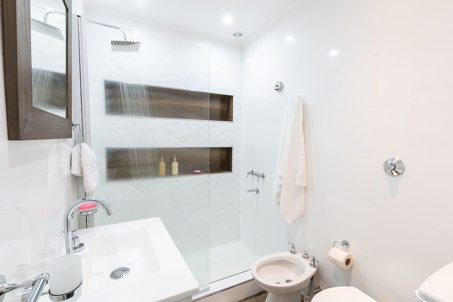 A bathroom with a sink , toilet , shower and mirror.