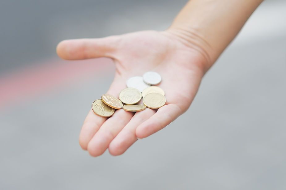 A person is holding a handful of coins in their palm.