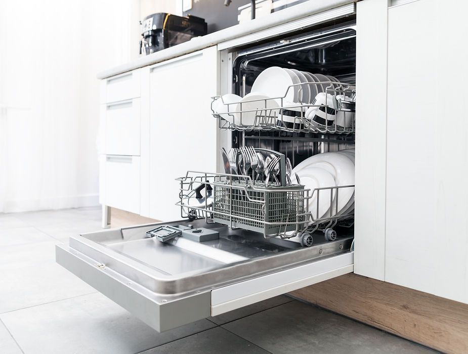 A dishwasher is open and filled with dishes in a kitchen.