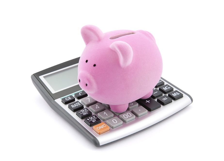 A pink piggy bank is sitting on top of a calculator.
