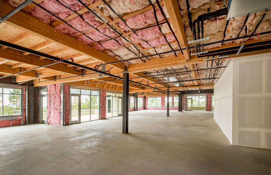 An empty building with a lot of windows and insulation on the ceiling.