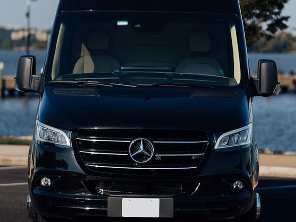 Black Mercedes-Benz van parked near water, with a dock in the background.