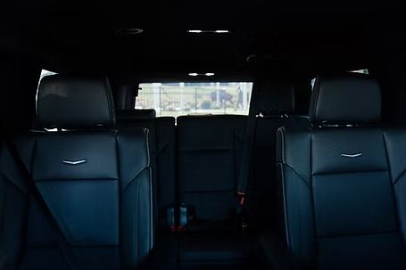 Interior view of a black SUV with leather seats and a rear window showing a building.
