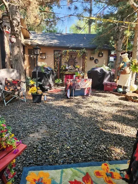 Backyard scene with gravel ground, shed, and various decorative elements.