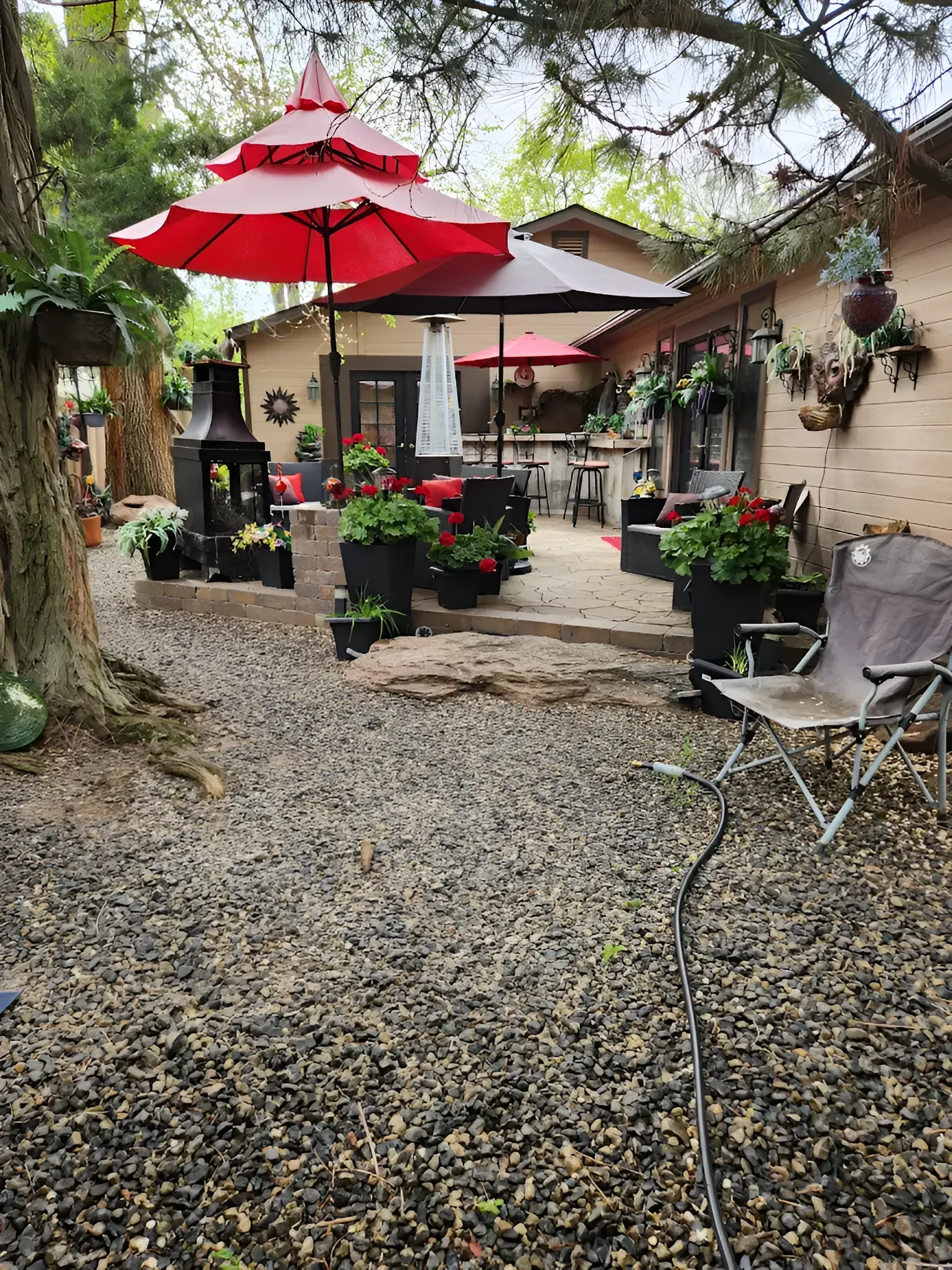 Outdoor patio with red umbrellas, potted flowers, and seating.