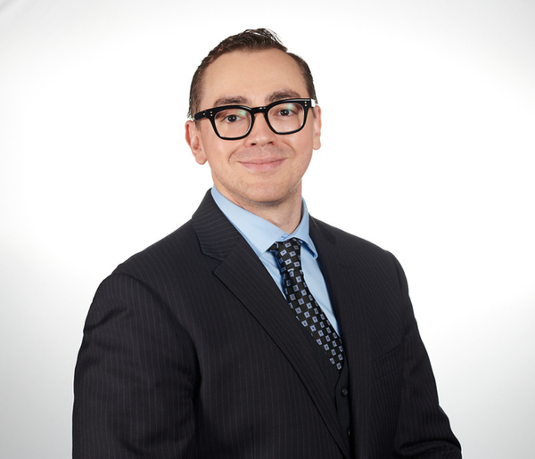 A man in a suit and tie is smiling for the camera