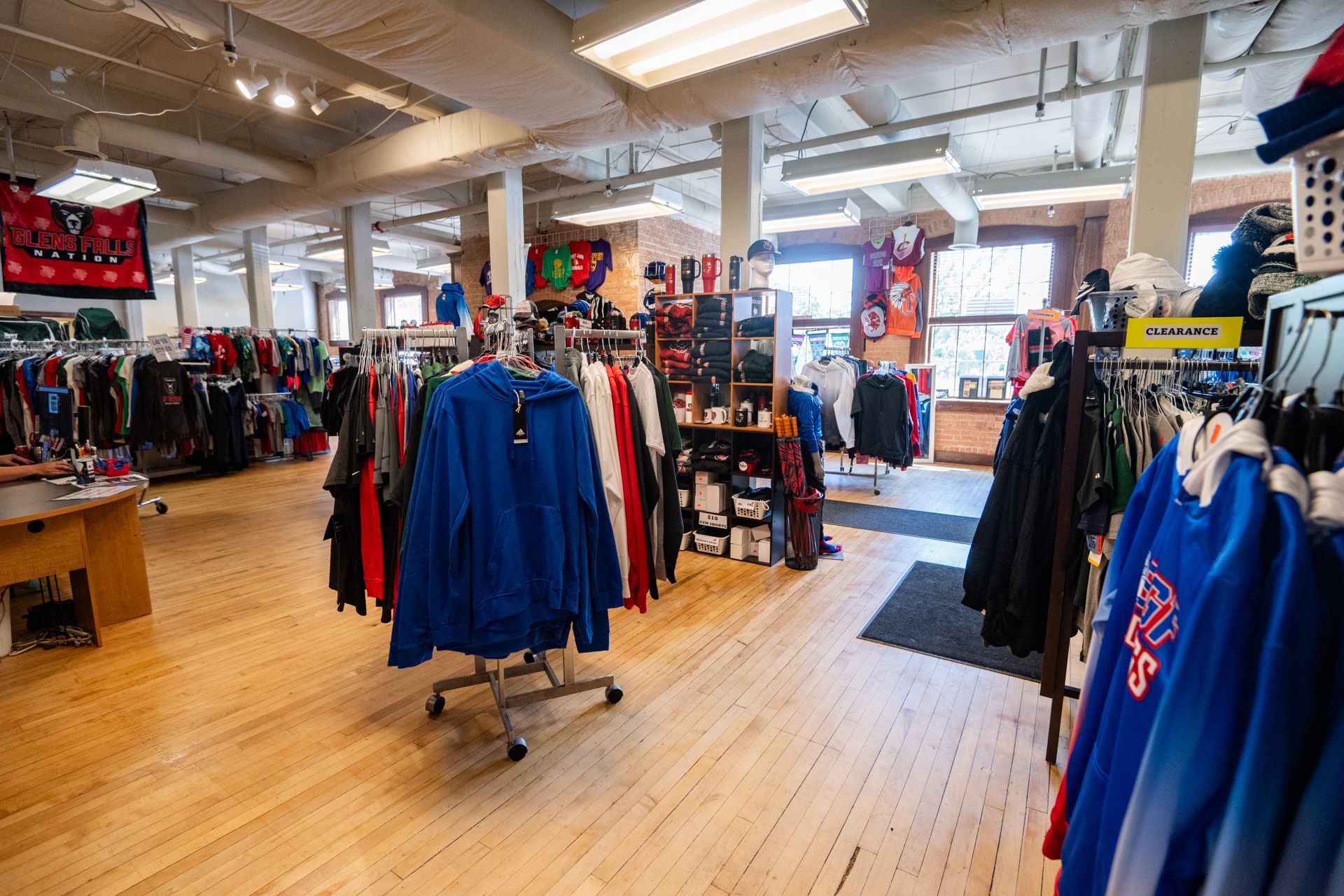 A bunch of shirts and hoodies are laying on a table