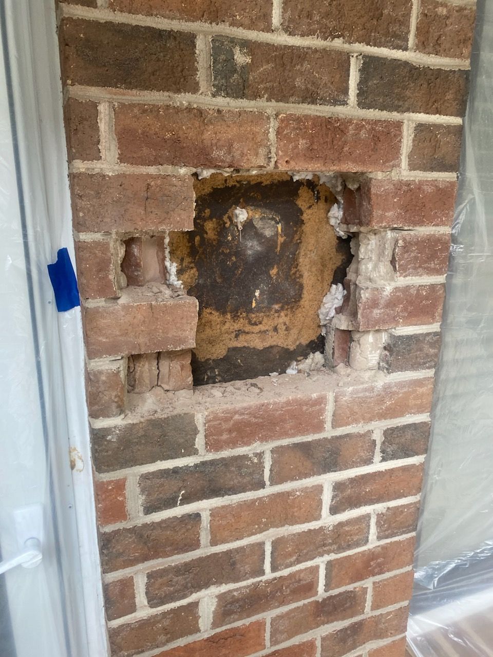 Brick column with a damaged rectangular section exposing a dark interior.