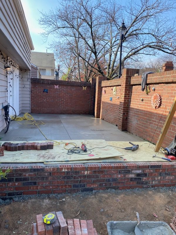 Patio under construction, featuring brick walls, concrete, tools, and materials.