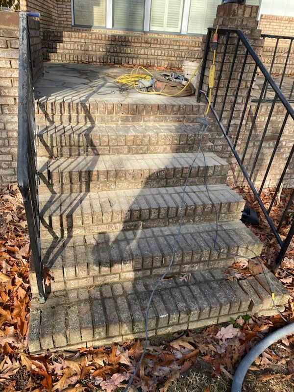 Brick steps leading up to a house entrance with black metal handrails.