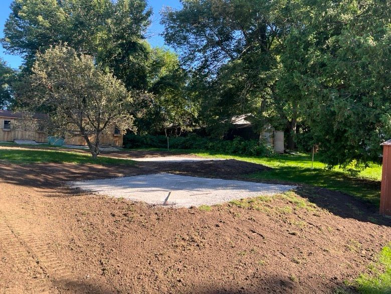 A dirt road leading to a house with trees in the background.