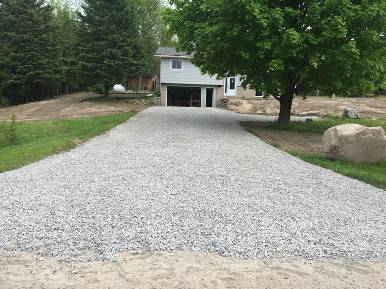 A gravel driveway leading to a house with a garage.