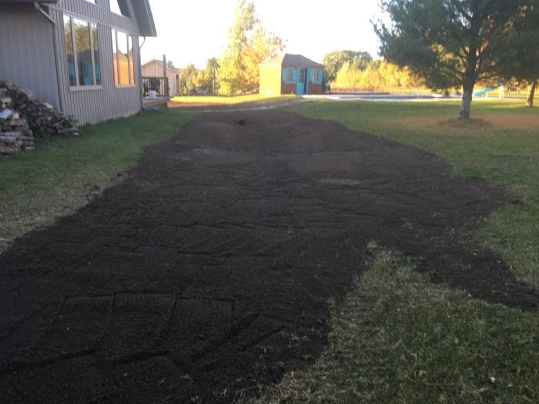 A driveway with a lot of dirt on it and a house in the background