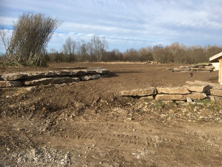 A pile of rocks is sitting in the middle of a dirt field.
