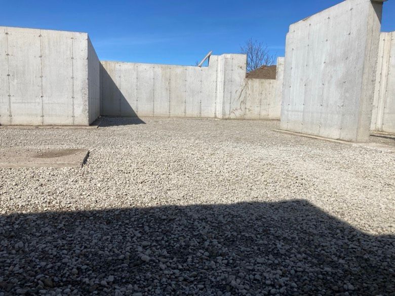 A shadow of a person is cast on the ground in front of a concrete wall.
