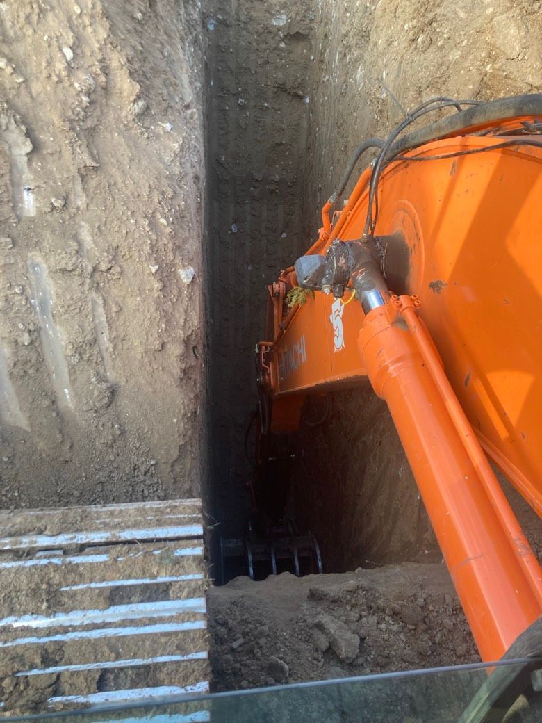 An orange excavator is digging a hole in the ground.