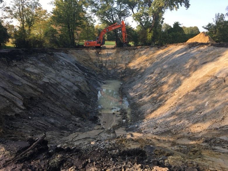 A large excavator is digging a large hole in the ground.