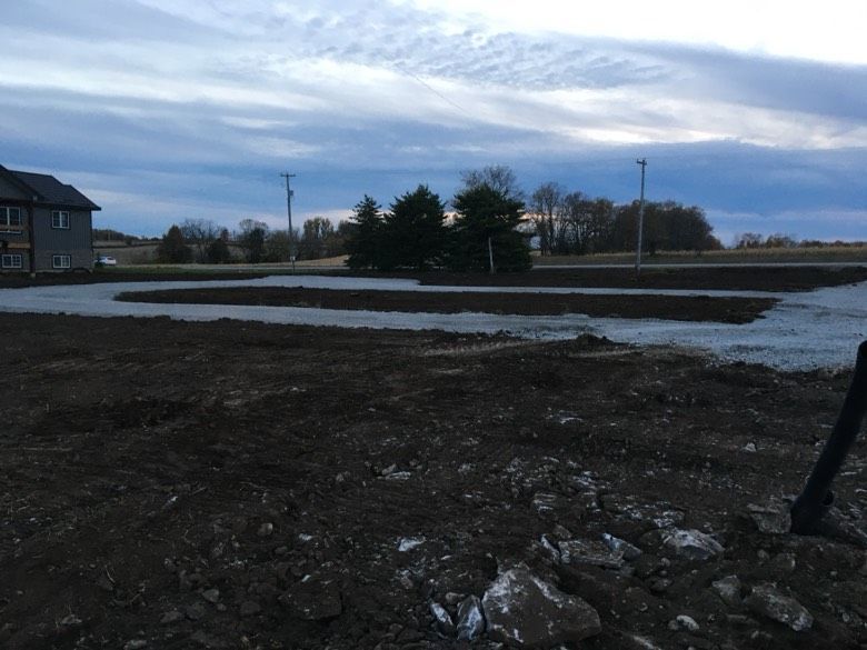 A large dirt field with a house in the background