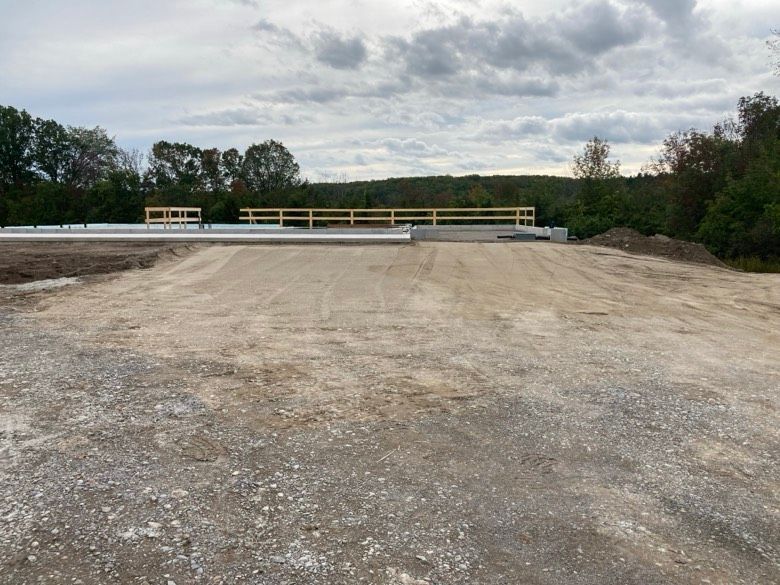 A dirt road with a bridge in the background