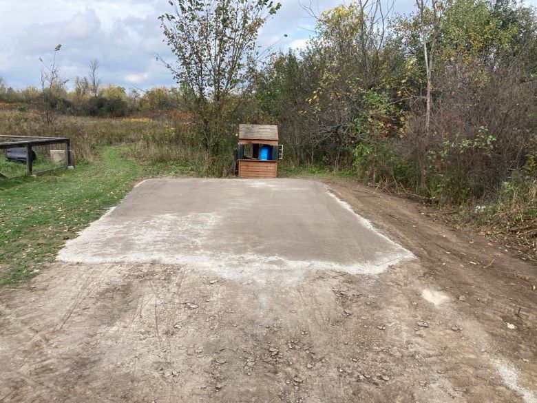 A dirt road with a trash can in the middle of it