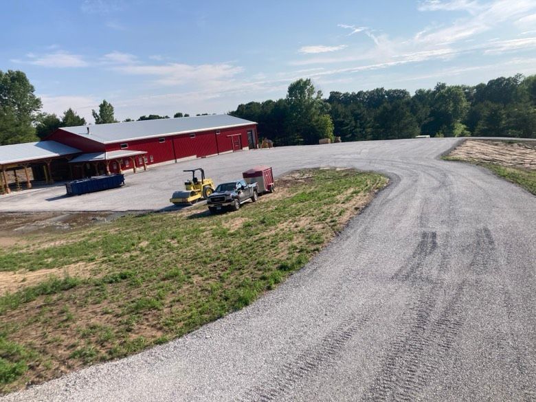 A dirt road with a red building in the background