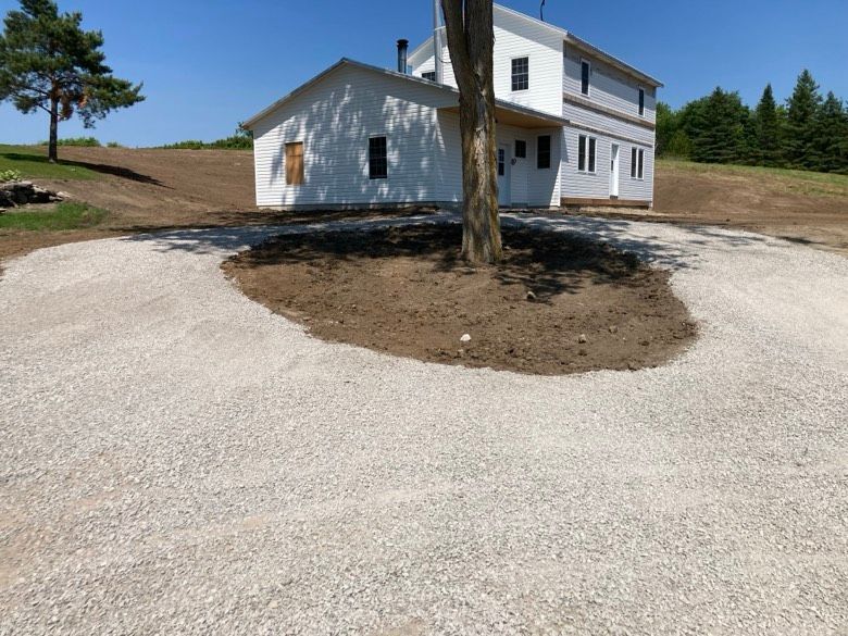 A white house with a gravel driveway in front of it