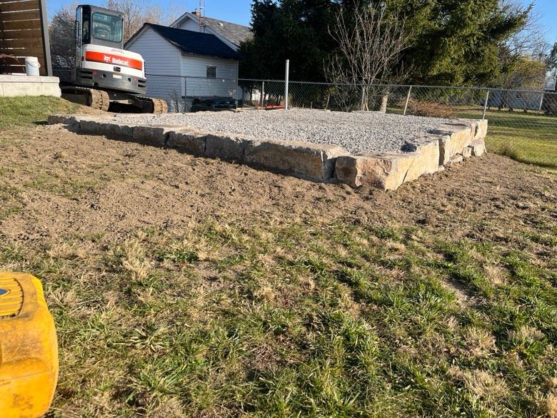 A bulldozer is moving gravel in a yard next to a house.