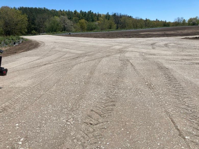 A dirt road with tire tracks on it and trees in the background.