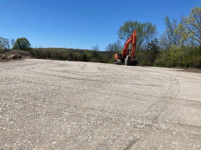 A large orange excavator is sitting in the middle of a dirt field.