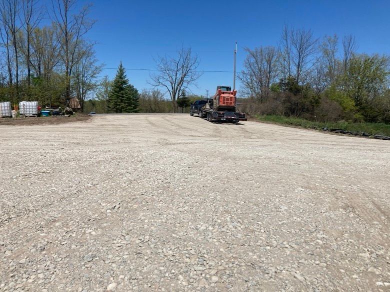 A truck is parked in the middle of a gravel road.