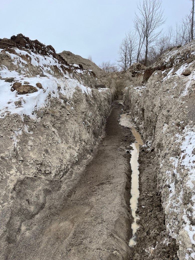 A muddy dirt road going through a snowy area.