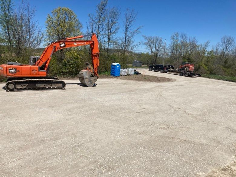 A large orange excavator is sitting in a parking lot.