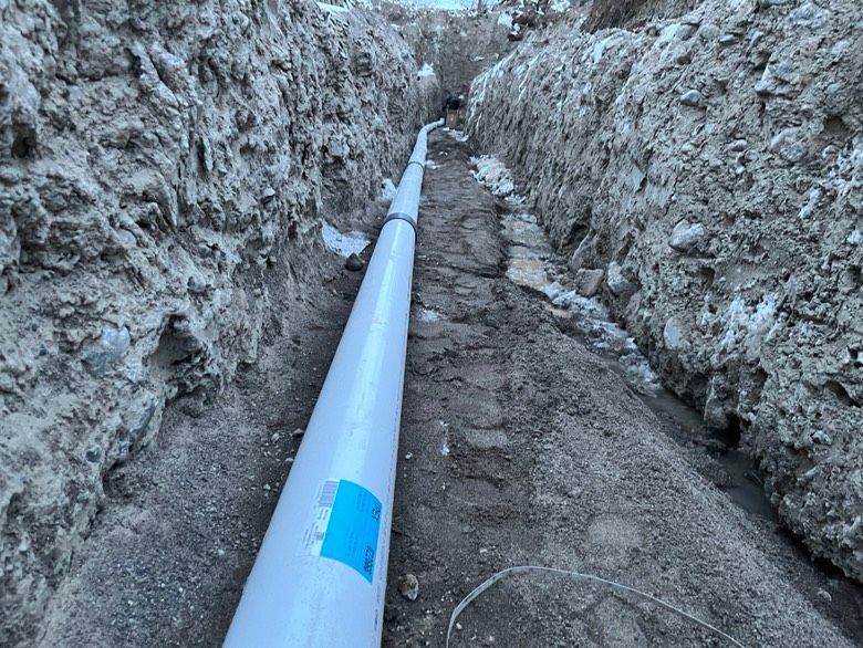 A white pipe is being installed in a trench.