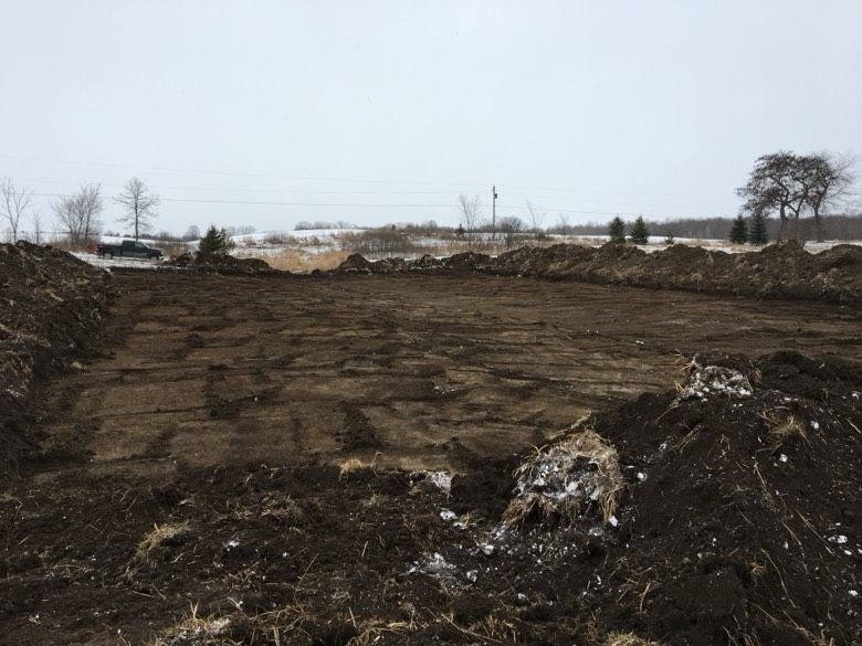 A large pile of dirt in a field with trees in the background
