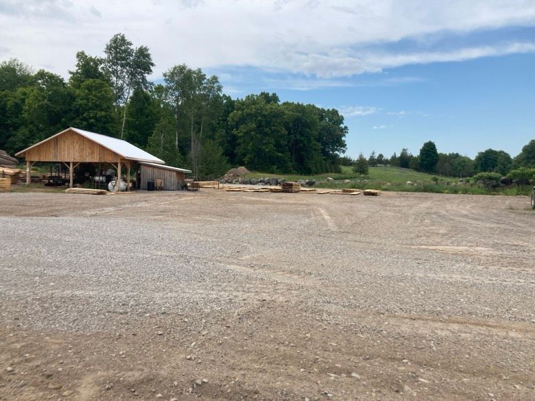 An empty gravel parking lot with a wooden building in the background