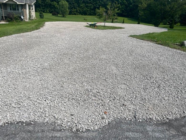 A gravel driveway with a house in the background.