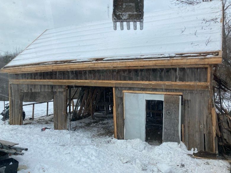 A wooden barn is being built in the snow.