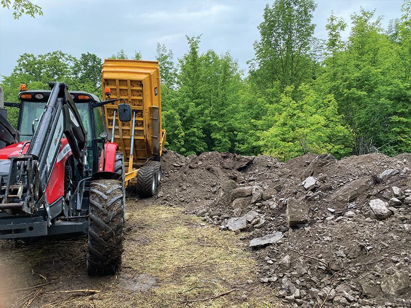 A construction worker is standing in front of a bulldozer at a construction site.