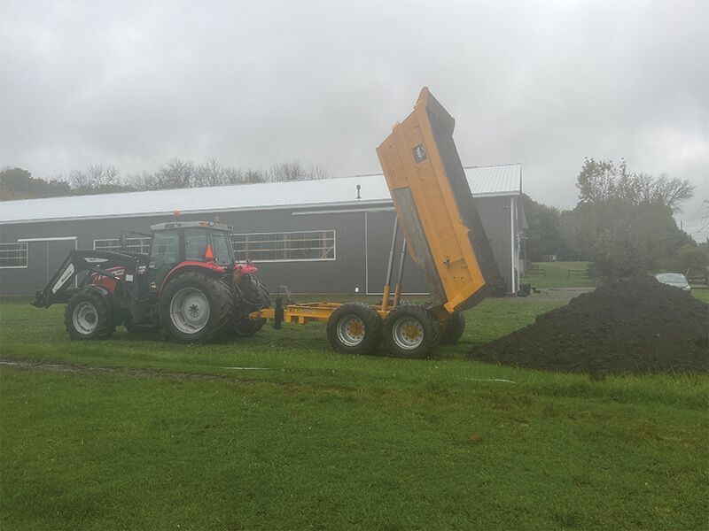 A bulldozer is digging a hole in the ground in a yard.