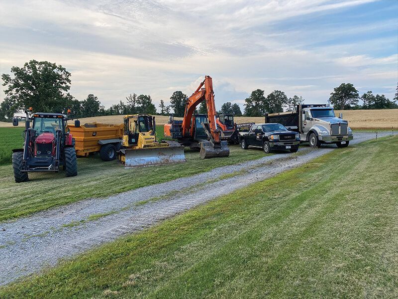 A dump truck is being towed by an excavator on a dirt road.