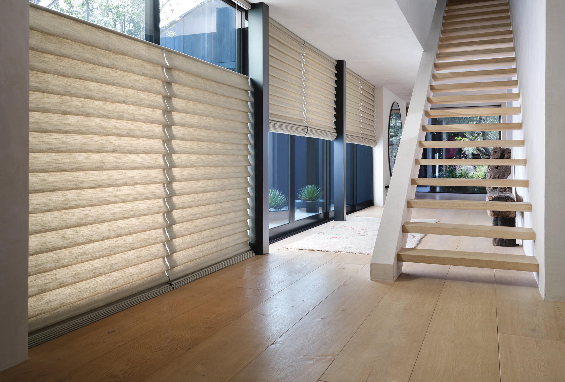 A hallway with a wooden staircase and blinds on the wall