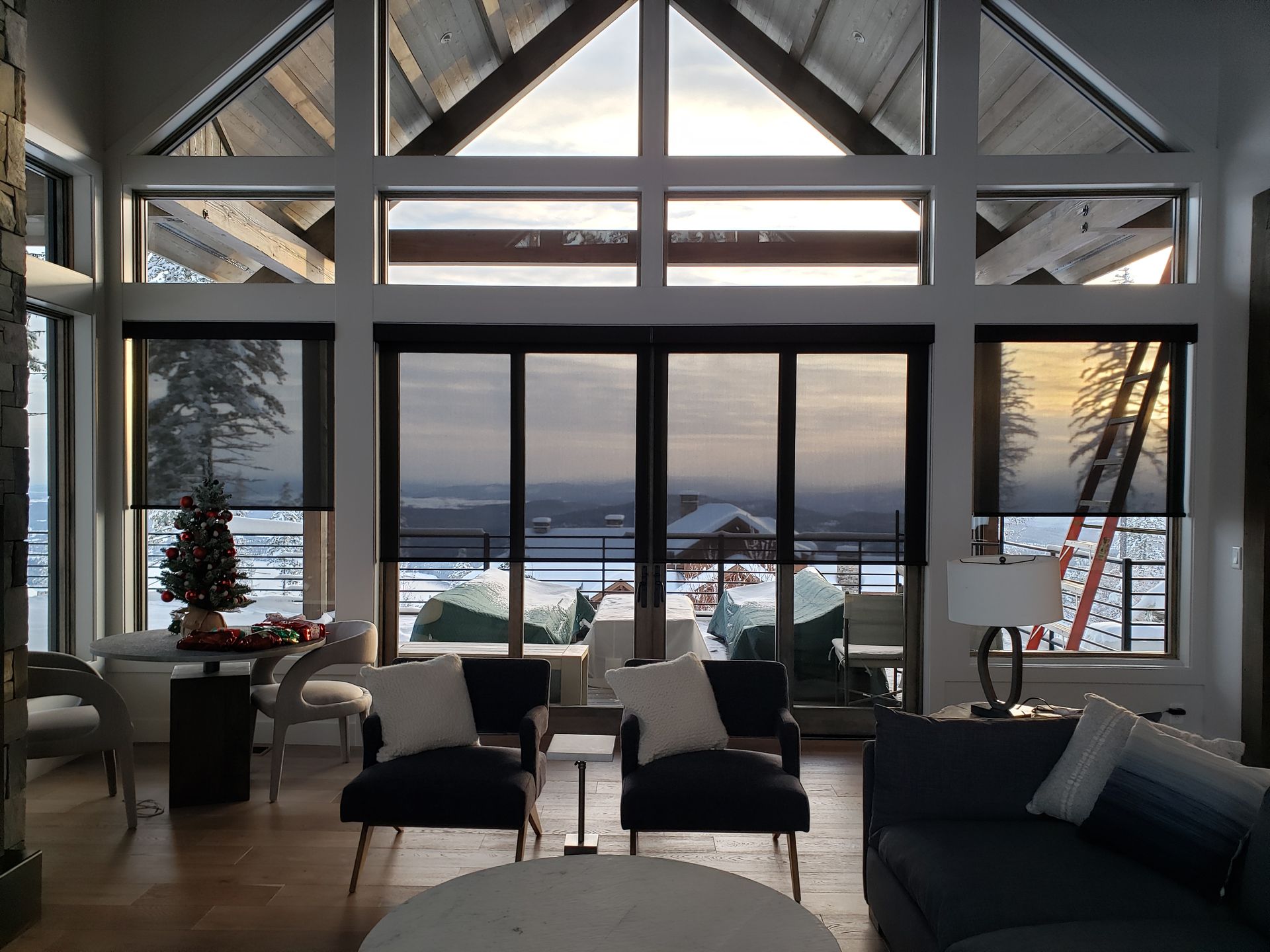 A living room with a brick wall and white blinds on the windows