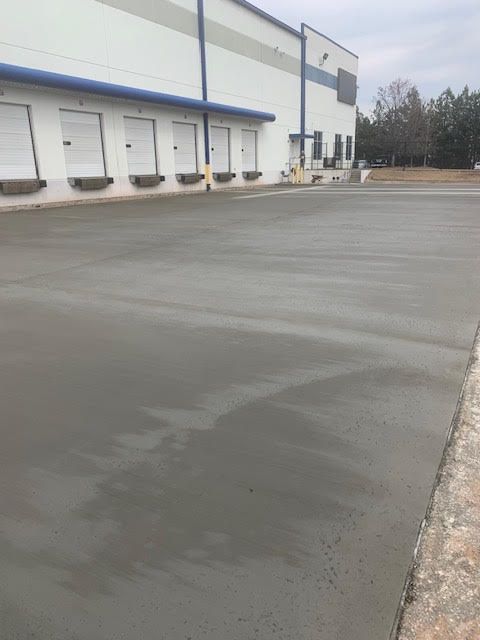 A man is using a broom to spread concrete on a sidewalk.