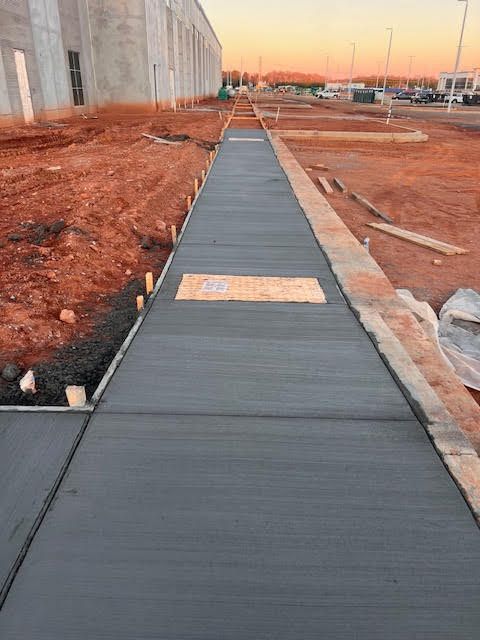 A sidewalk is being built in the middle of a dirt field.