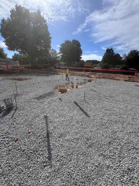 A construction site with gravel and trees in the background